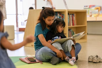 A mother and child sit with a book at the State Library of Queensland