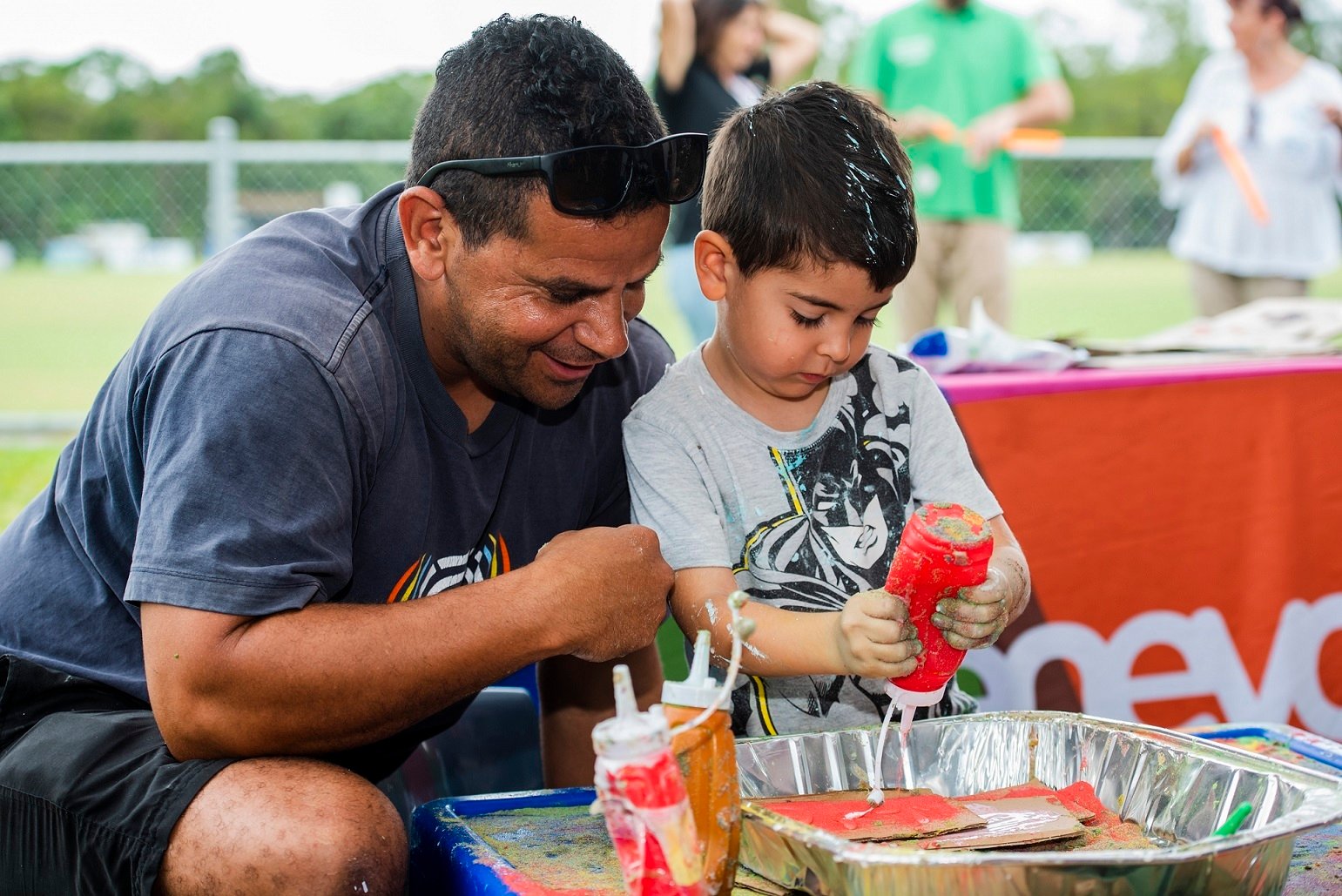 A male caregiver and his child participate in a messy play activity. 
