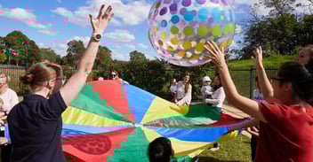A variety of images showing children engaging in physical play, such as running, obstacle course, playing with balls and coloured parachutes, sliding down a slide. 