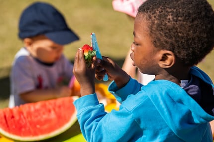 Adult supervising child using knife to cut a capsicum