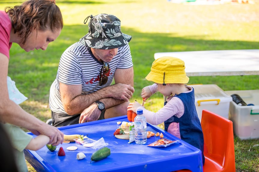 Adult supervising child using knife to cut a capsicum