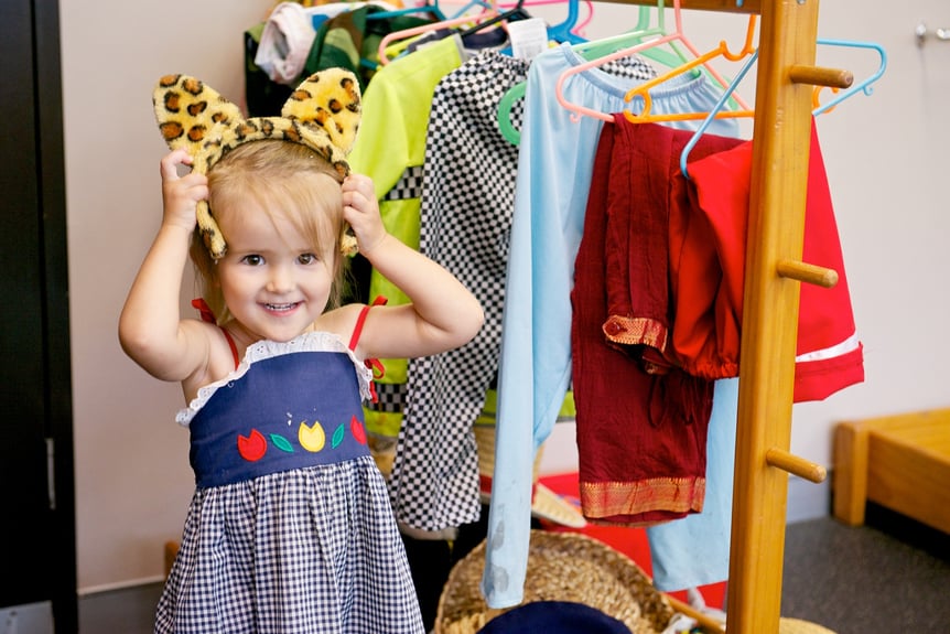 Child preparing for imaginative play, pushing cat ear costume back through their hair.