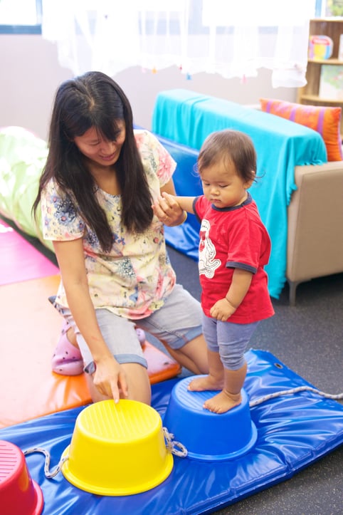 Toddler completing an obstacle course with support of parent