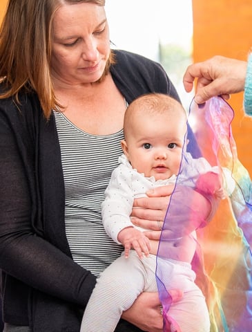 A baby explores scarves and music play