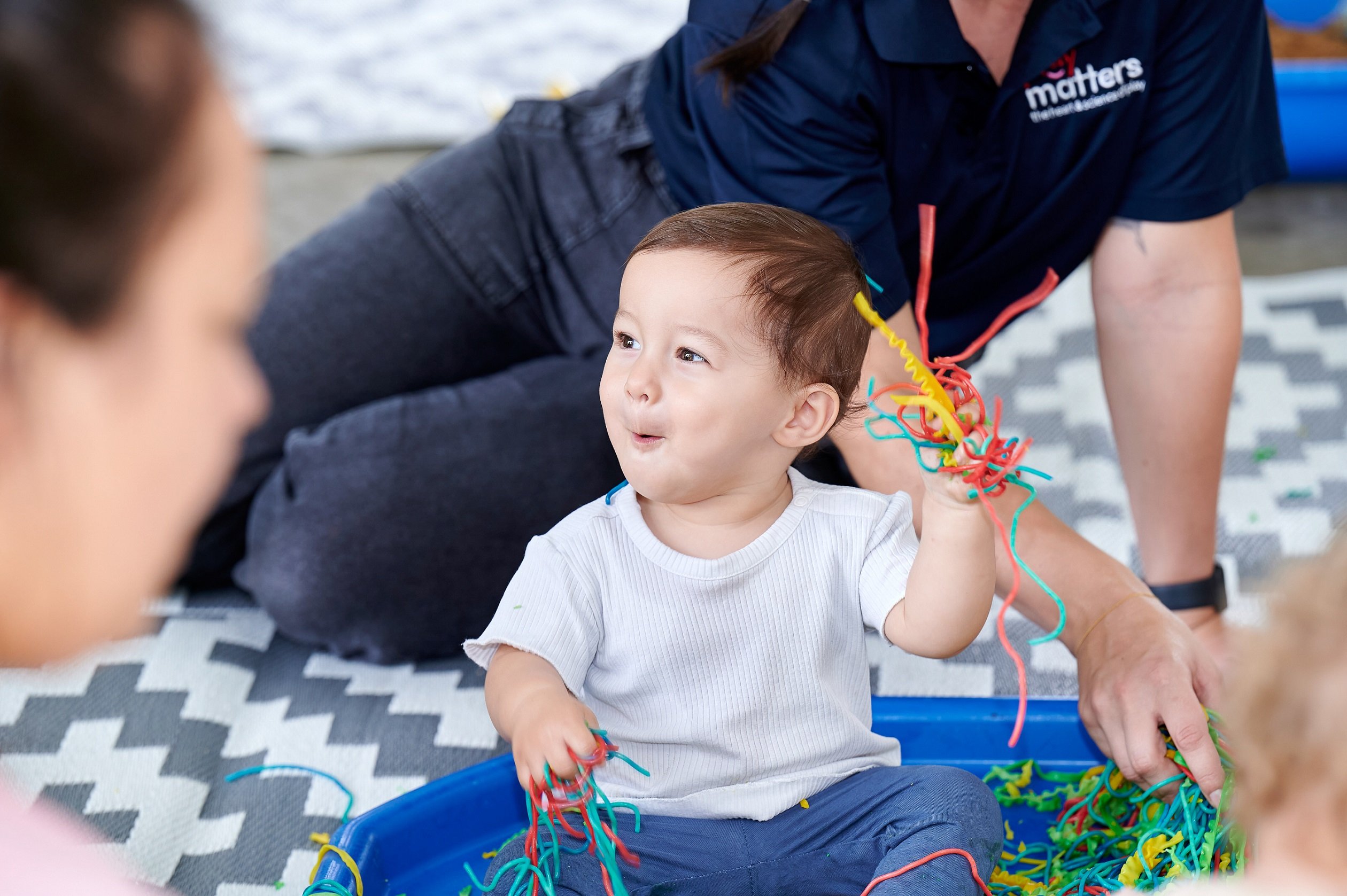 Baby playing with rainbow spaghetti at the Messy Play Matters event on the Sunshine Coast.