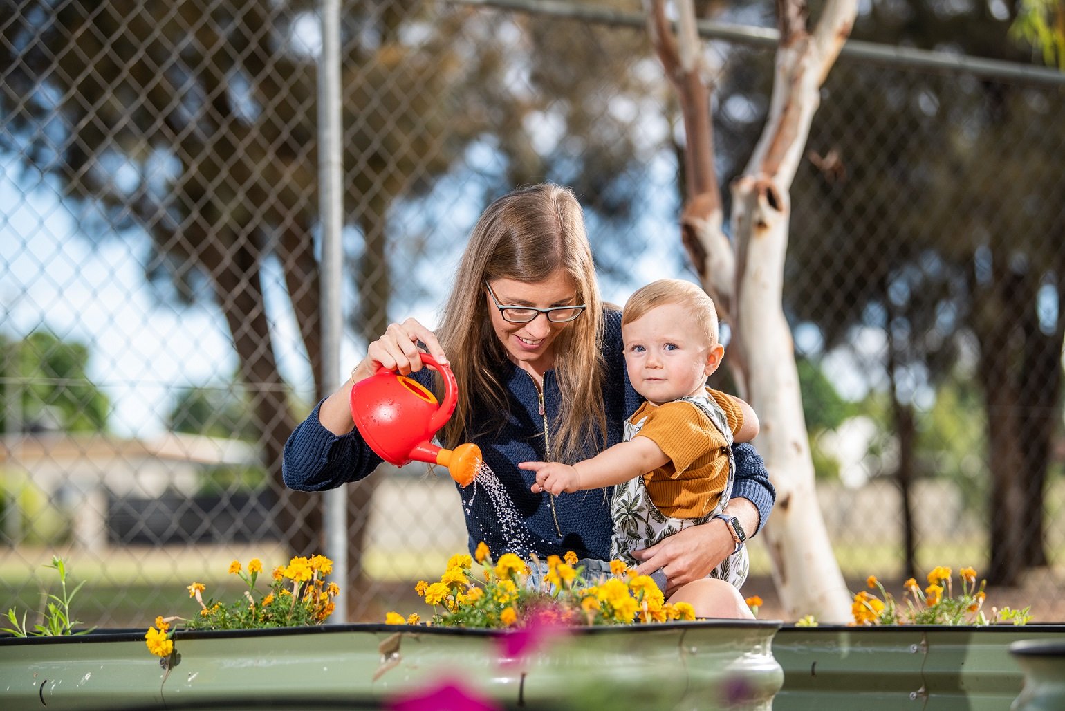 Parent and toddler watering the garden at the Play Matters Mt Isa Hub.