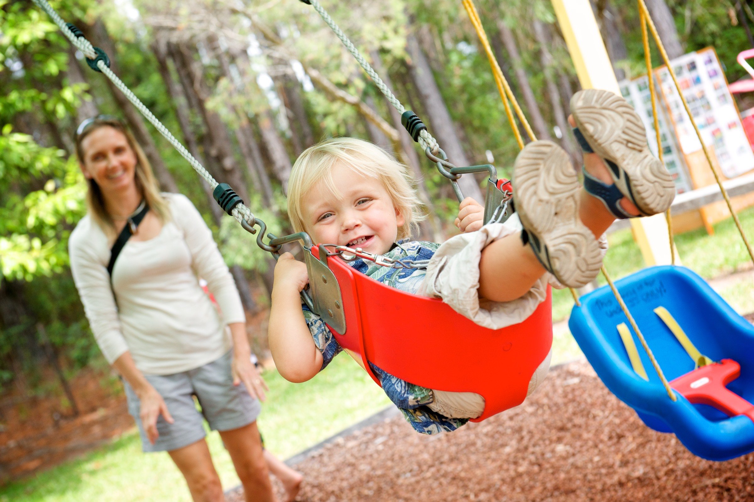 Parent pushing child in swing at the Sunshine Coast Hub