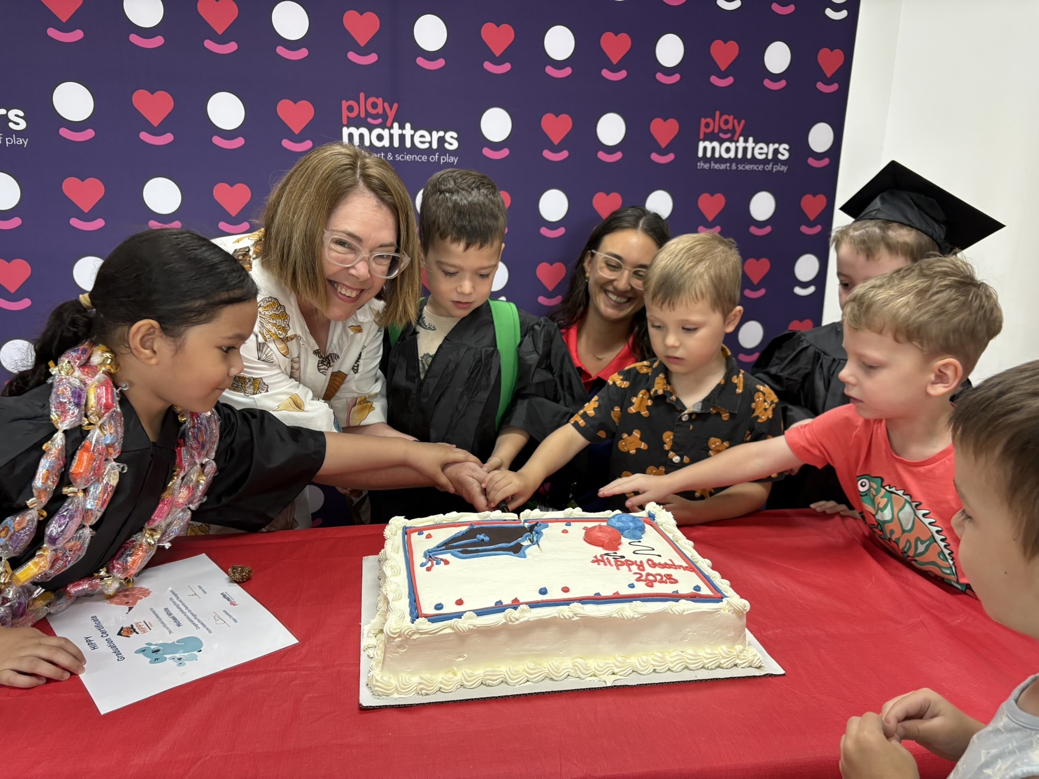 HIPPY Goodna graduates with CEO Penny Creamer at Play Matters Hub in Ipswich cutting a cake. 