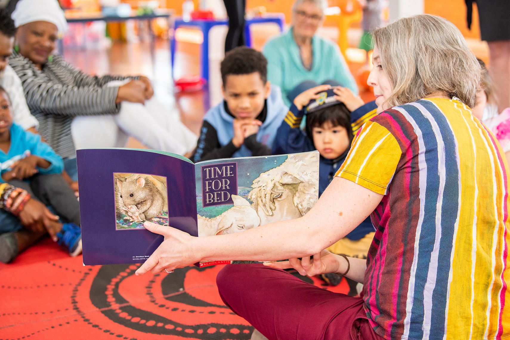 Playgroup volunteer reading a story to children and families