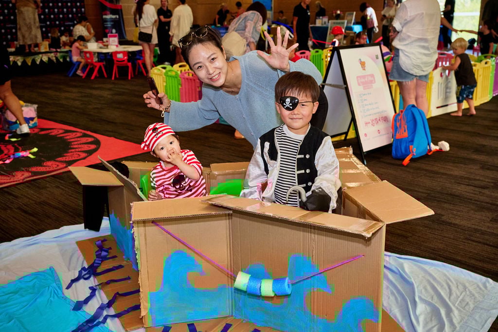Two children are dressed up as pirates and in a box boat
