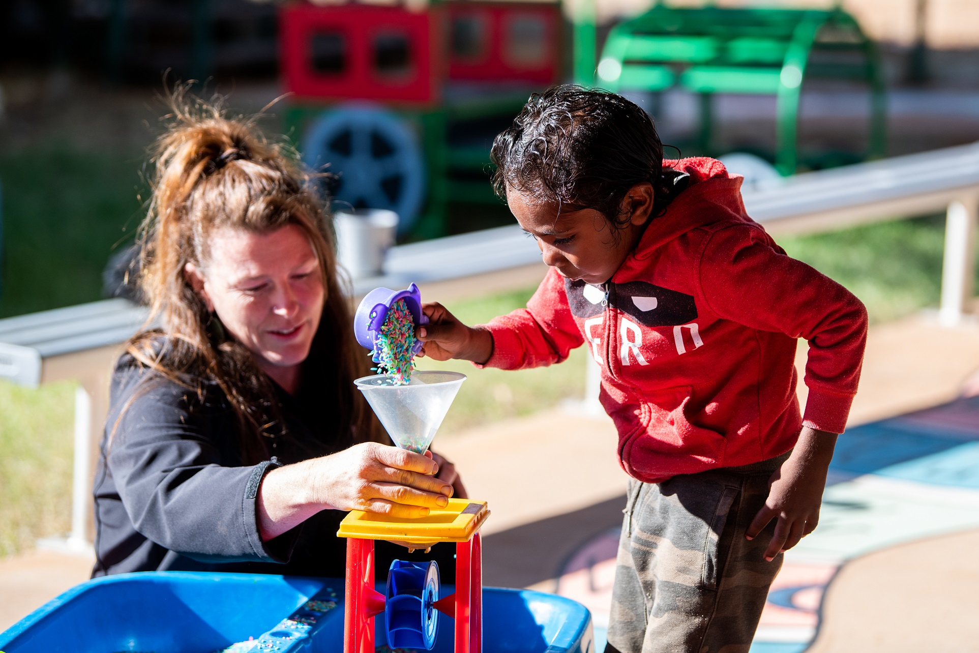 Facilitator with child and rice play